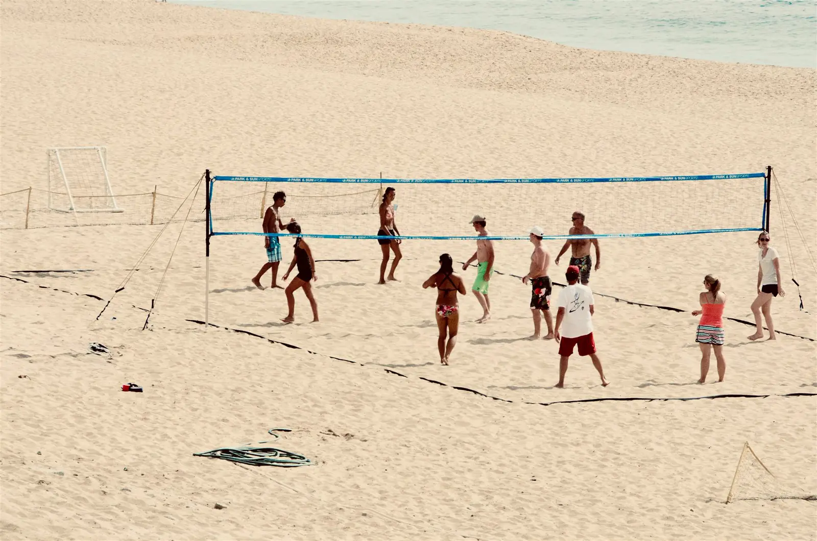 Friendly beach volleyball game on a wide sandy beach by the sea.